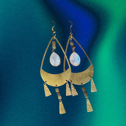Gold earrings with teardrop-shaped stones on a blue and green gradient background