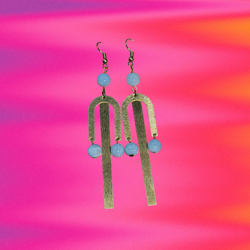 Gold and blue earrings on a colorful abstract background