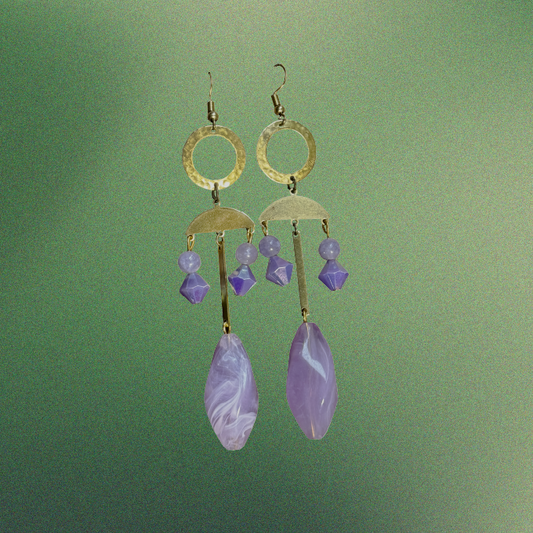 Gold earrings with purple stones on a green background