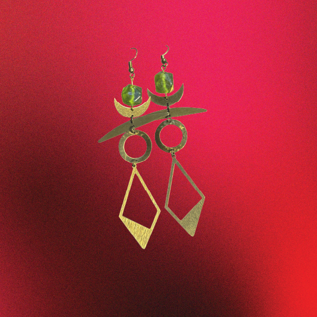 Pair of gold and green earrings on a red background